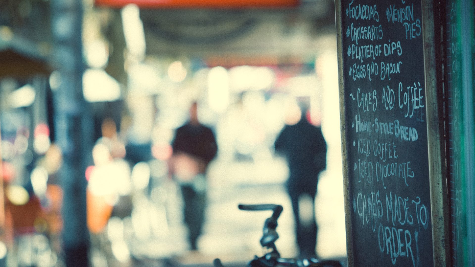AI slop in restaurant menus contrast: a hand-written chalkboard cafe menu on a busy city sidewalk