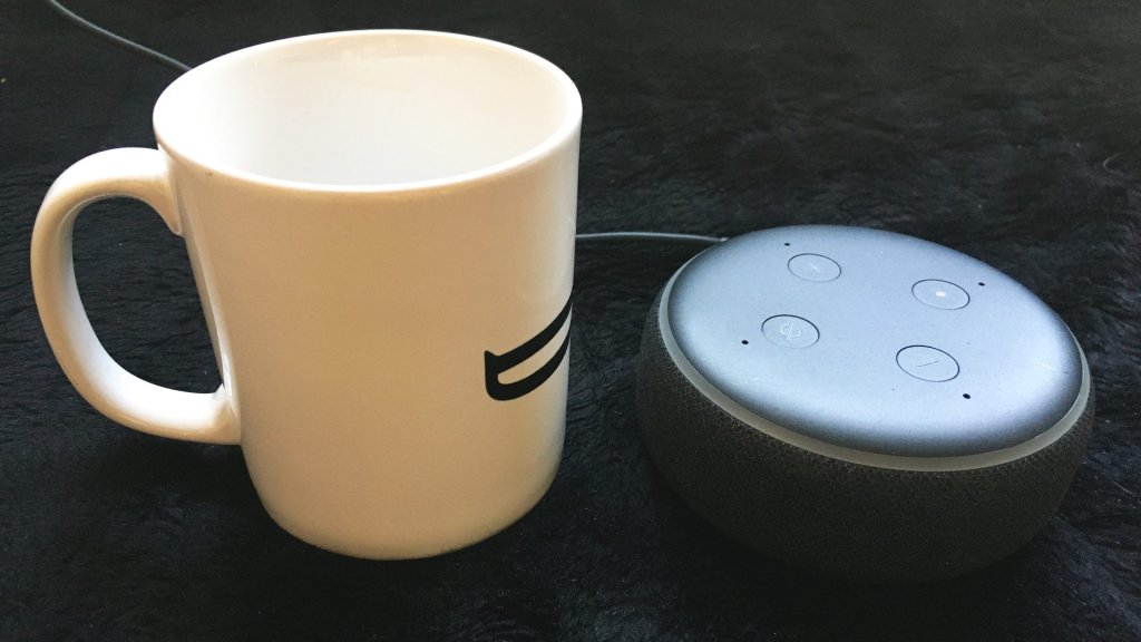 alexa plus free for prime members: an Amazon Echo Dot beside a coffee mug on a dark surface