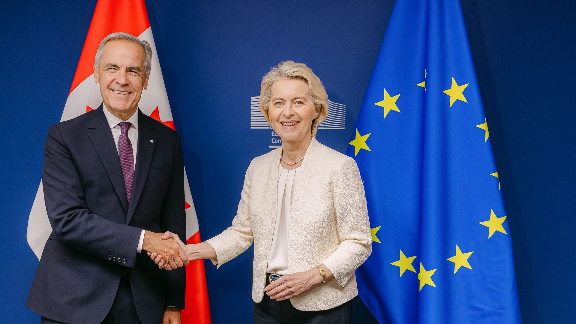 canada eu ai infrastructure contracts: Mark Carney and Ursula von der Leyen shake hands in front of Canadian and EU flags